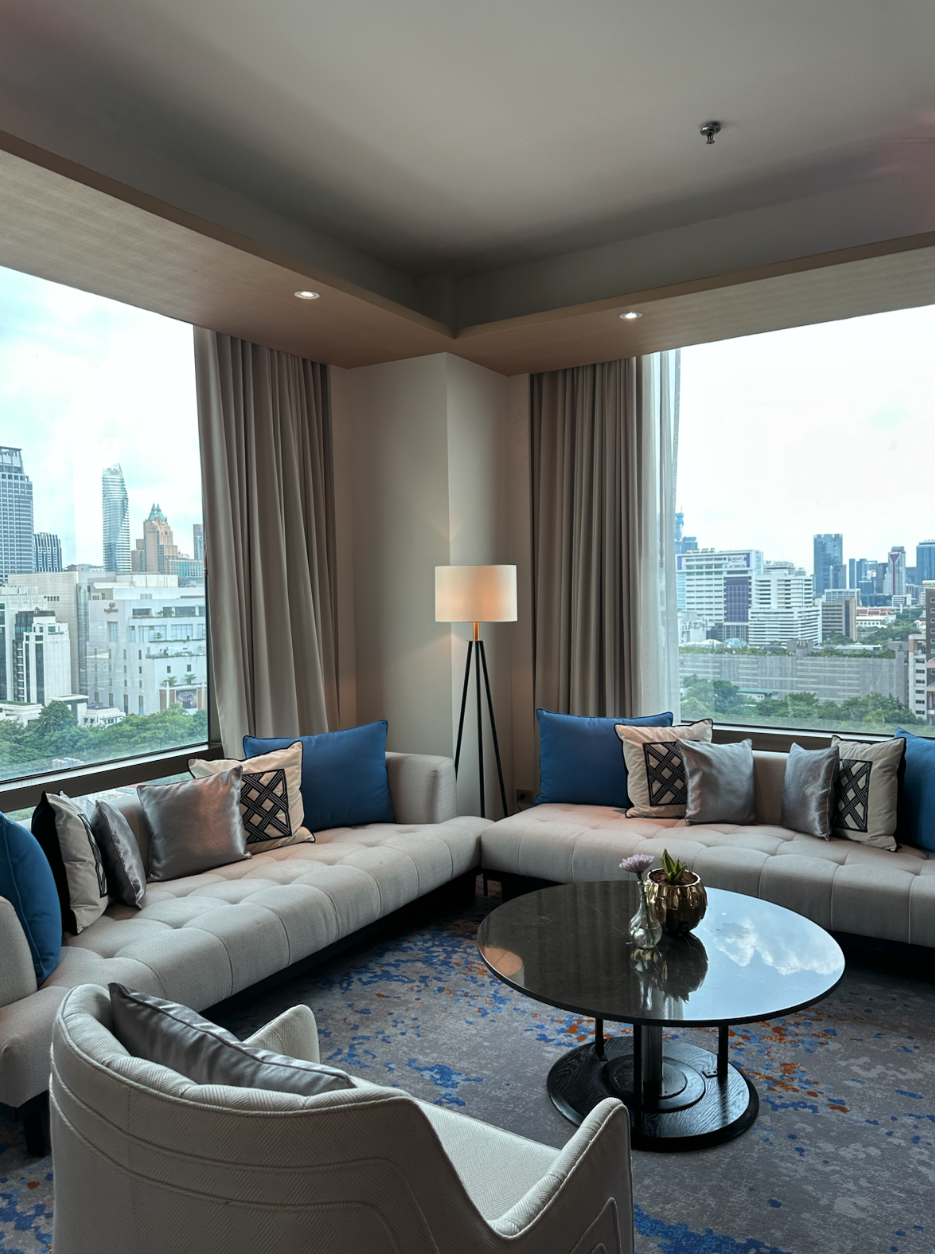 두 면의 통유리창과 흰색 소파가 보이는 VIE Hotel Bangkok 코너 스위트